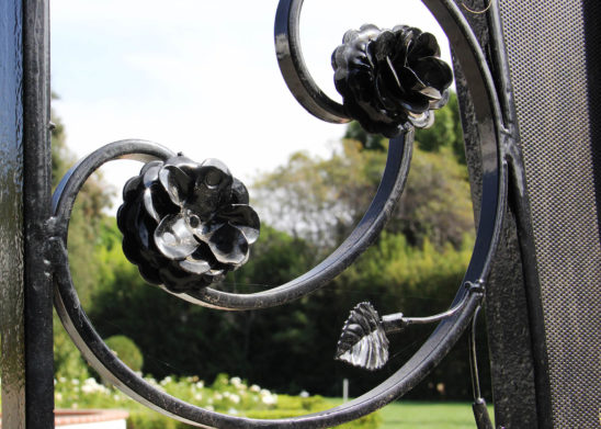 side close up of handmade flower and leaf appliques on wrought iron gate